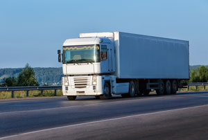 white moving truck driving down a country road